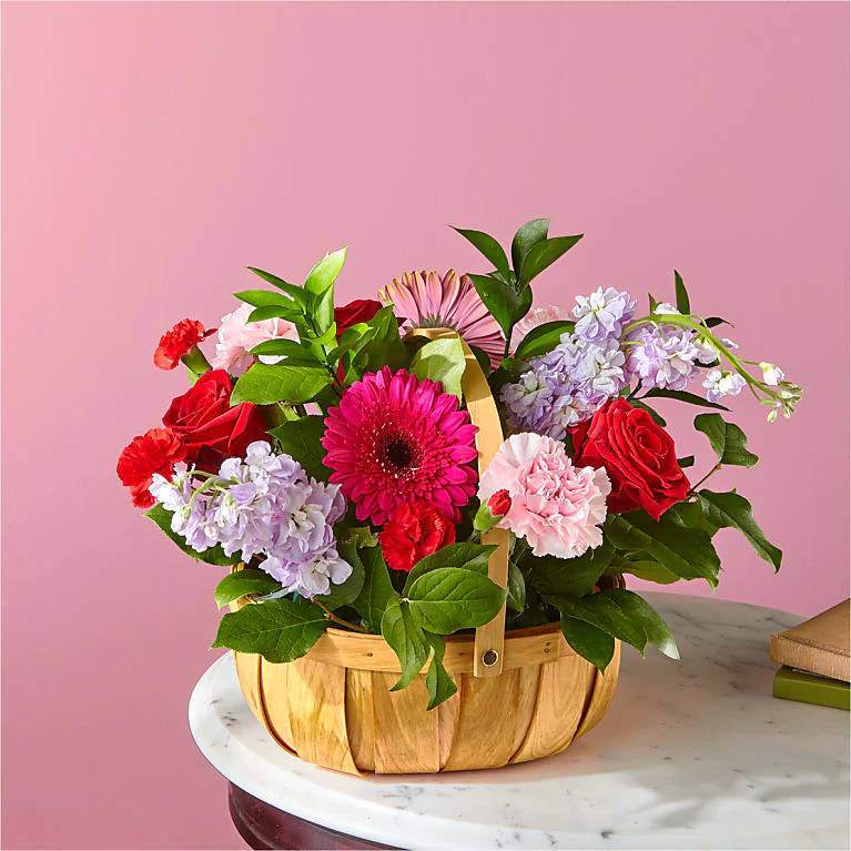 This bountiful basket of roses, carnations, and hot pink Gerbera daisies will