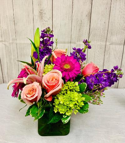 A modern compact low arrangement of vibrant high end blooms such as