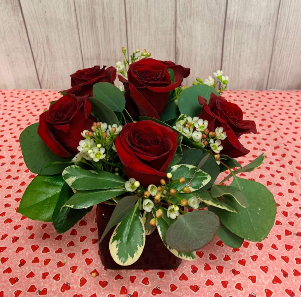 A half dozen red roses arranged low and compact.
