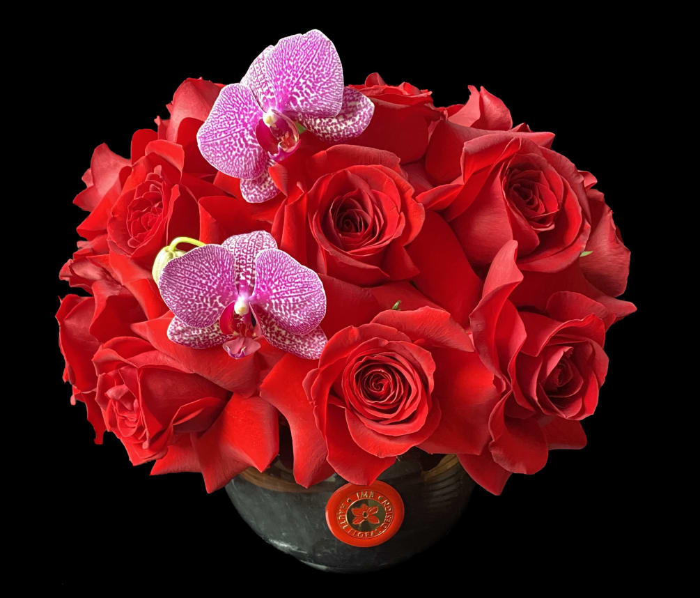 Red roses and orchids in black nero marquina marble vase.
