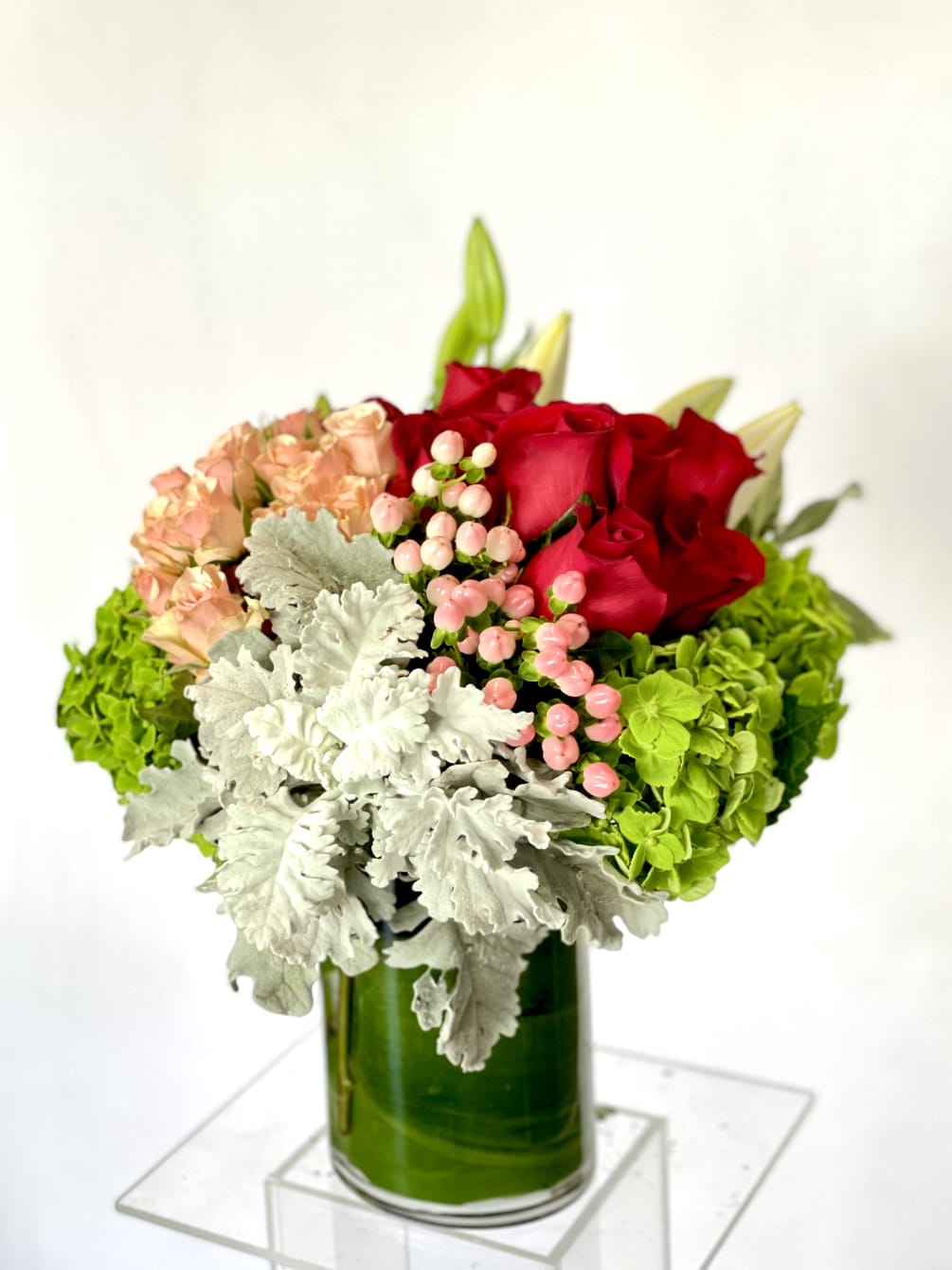 Red roses, peach spray roses, green hydrangeas, and asiatic lilies in a