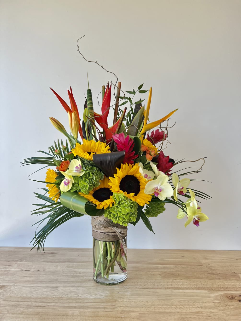 Beautiful one-sided arrangement with a mixture of sunflowers, tropical, orchids, and more.