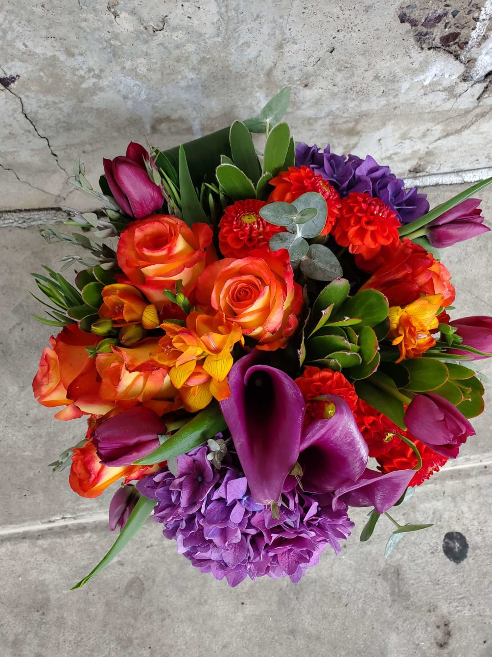 An organic explosion of colors mix with hydrangea, purple callas, tulips and