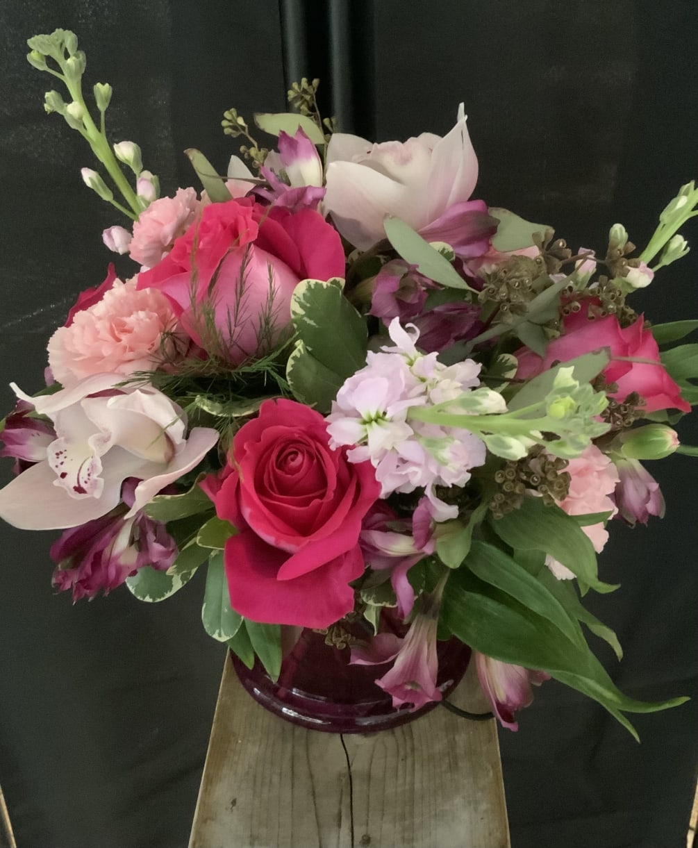 Beautiful hot pink roses, fragrant stock and cymbidium orchids are the focus