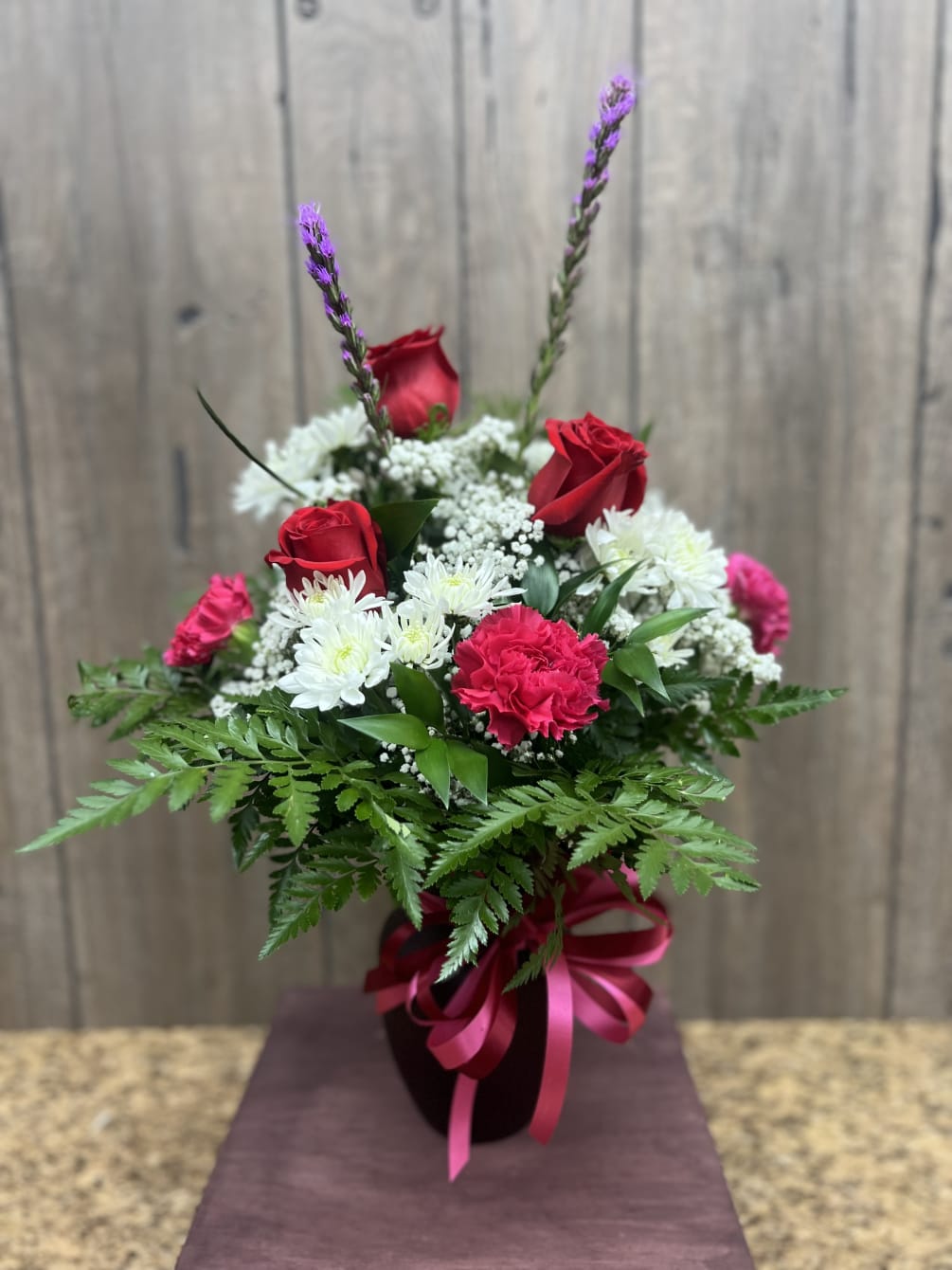 Red roses mixed with red, white, pink, and purple flowers in a