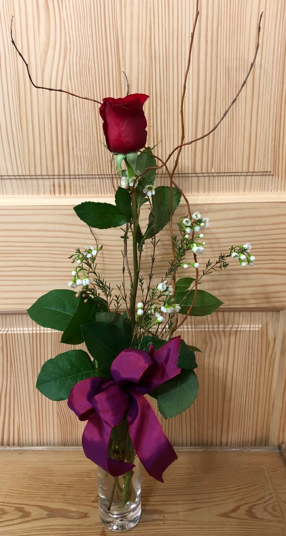 Single rose in a bud vase with greenery and filler. This can