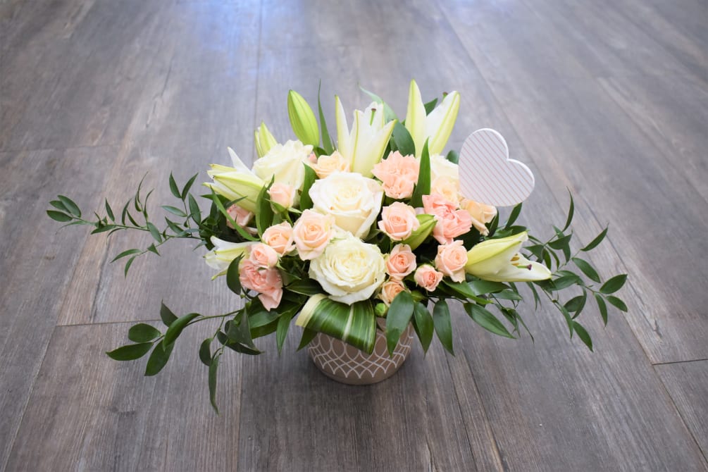 Blush and white roses and bright white lilies celebrate the hope and