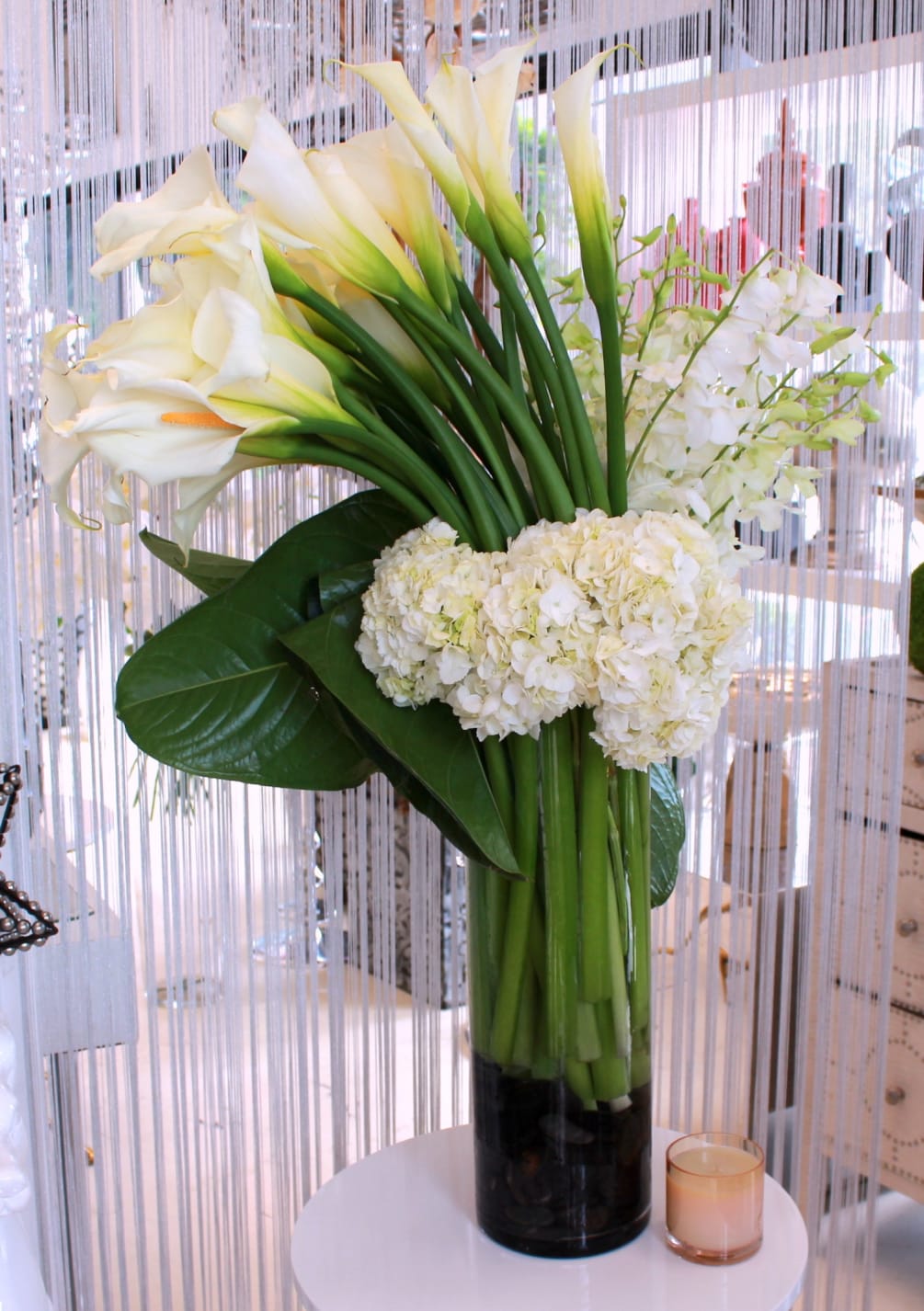 Sculptural calla lilies with white hydrangeas and orchids in a large glass