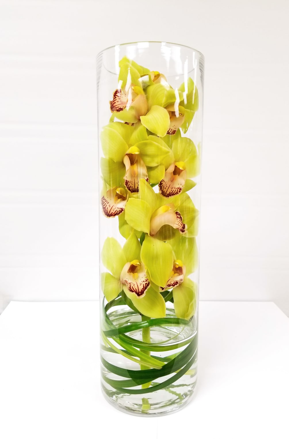This sophisticated fresh floral arrangement features long-lasting cymbidium orchids with swirled lily