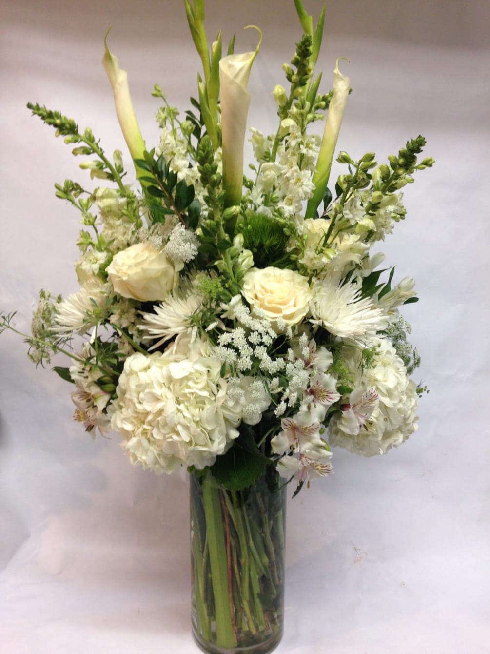 This arrangement contains a seasonal blend of white flowers including elegant calla