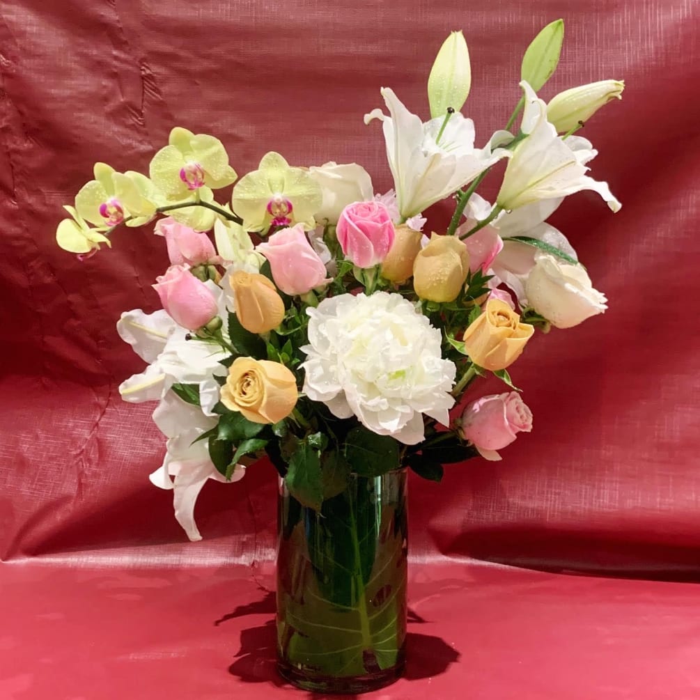 Custom arrangement of Casablanca lilies, roses &amp; orchids in clear glass vase