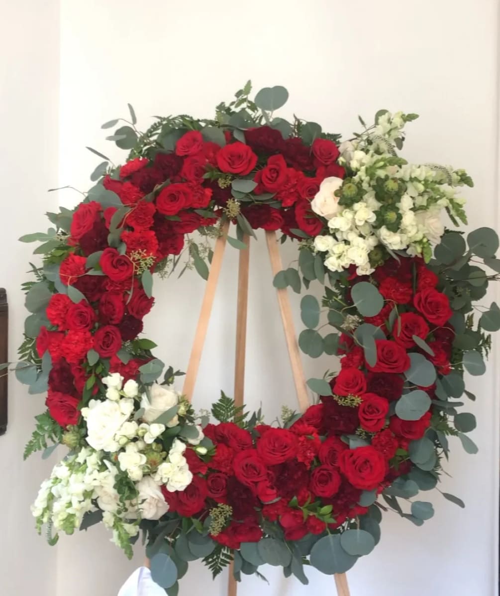 Red sympathy wreath with touches of white florals creating a beautiful tribute
