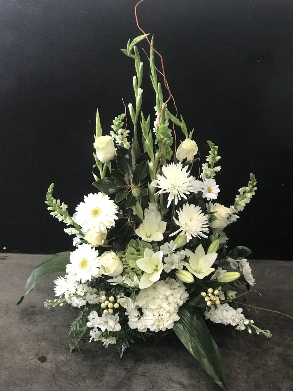all white flowers arranged in a fan like basket for a funeral