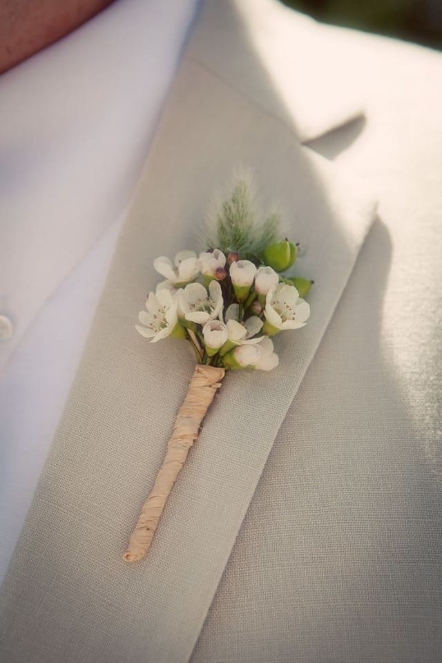 Wax flowers accented with greenery wrapped in twine for a rustic look.