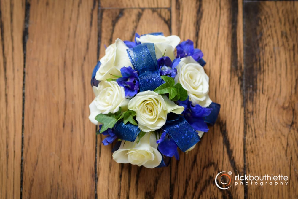 Shown as Standard.
White spray roses, navy delphinium and ivy come designed on