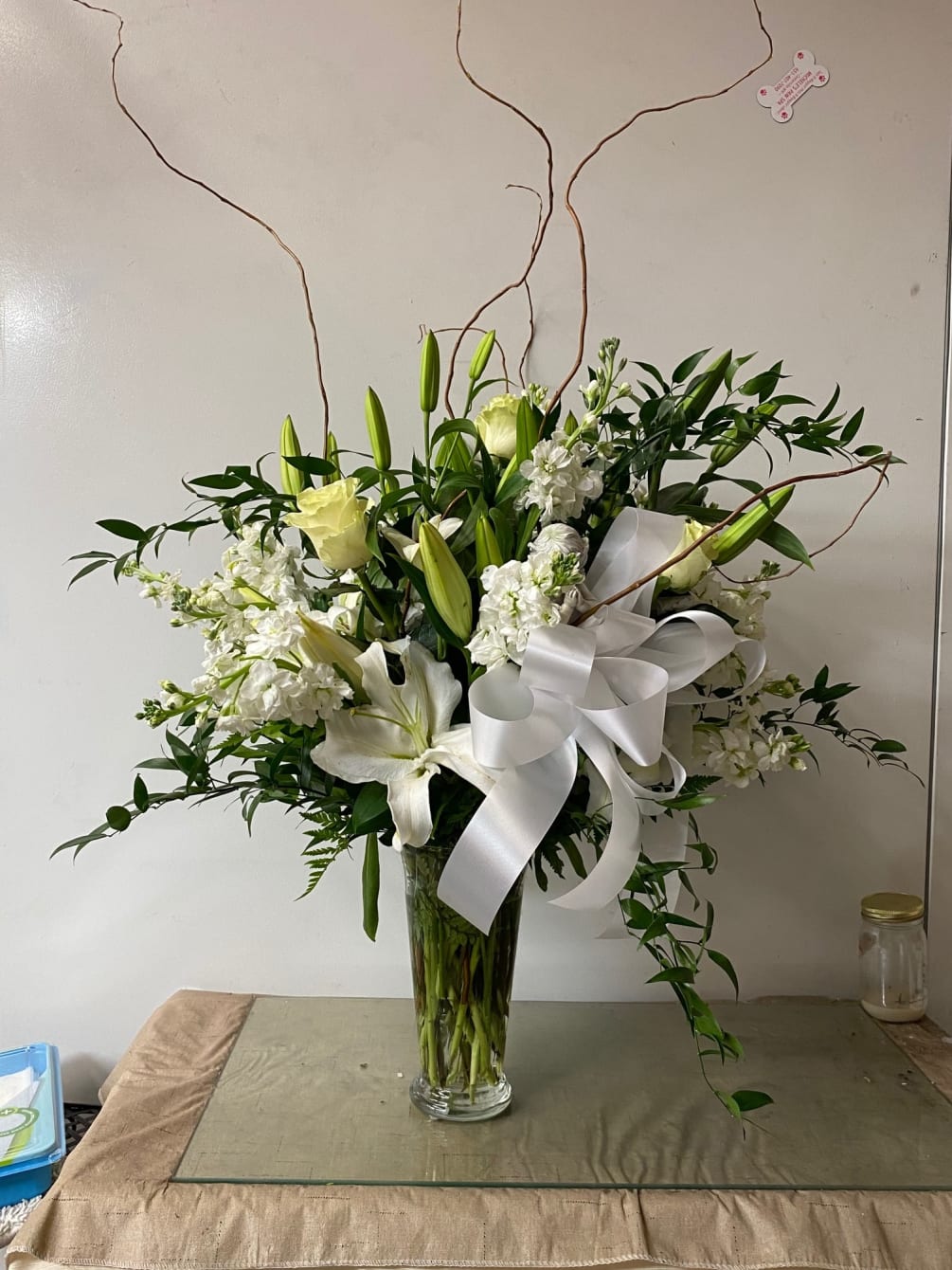 White roses, stock, snapdragons, curly willow and lilies with mixed greens. 