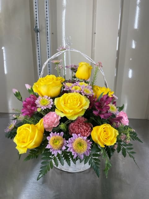 Mixed cut arrangement in a white basket with yellow roses, mini pink