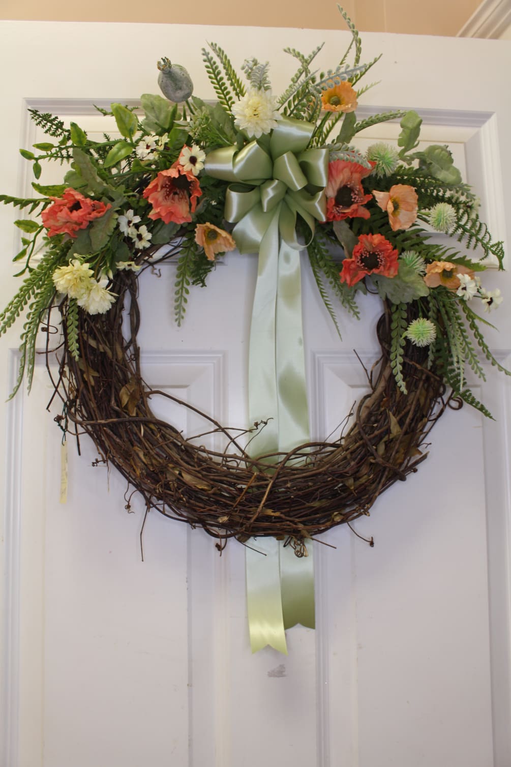 soft greens and peaches gather on this grapevine wreath