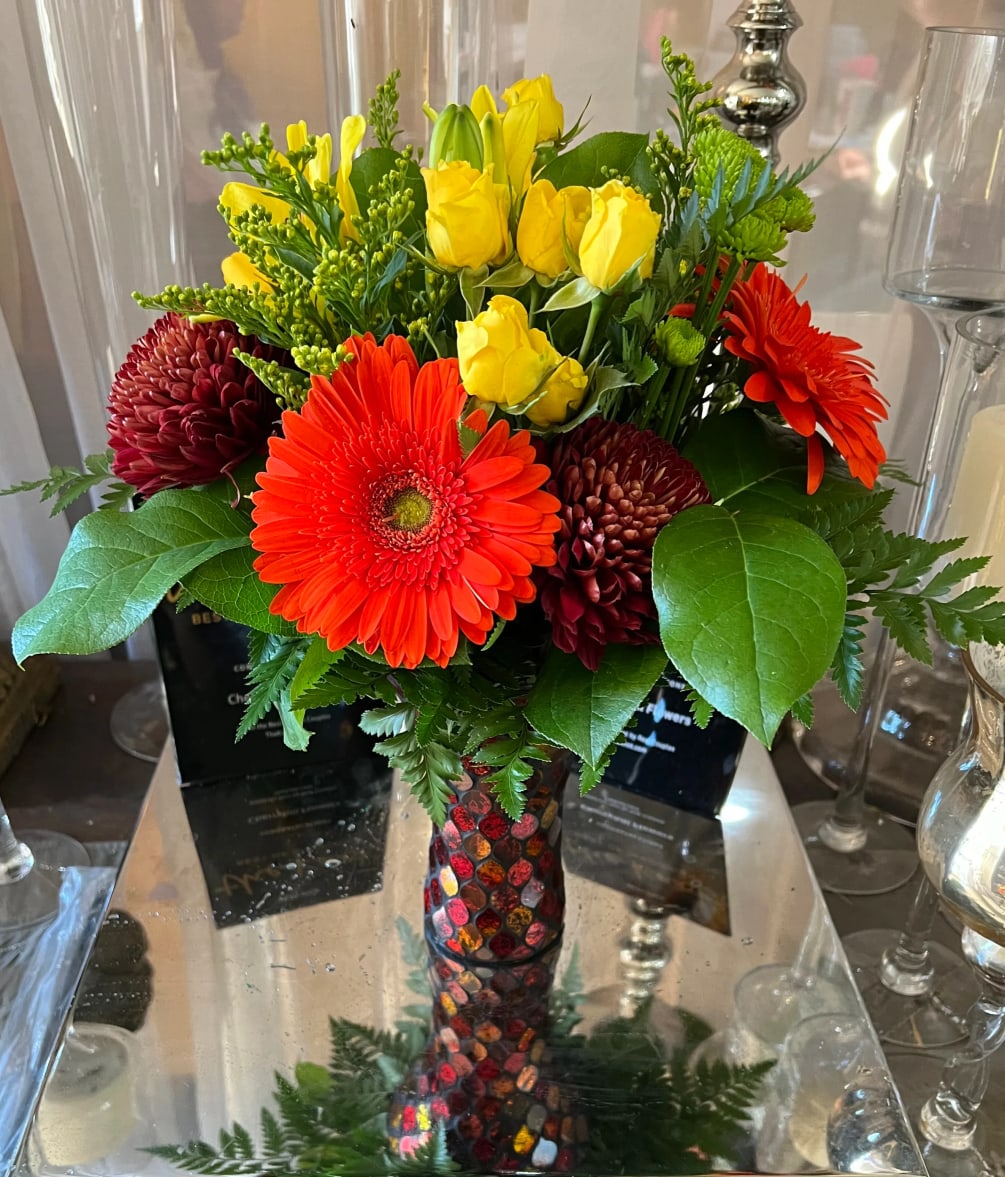 Gerber daisies, spray roses, mums, with a fall colored vase. 
Shown in