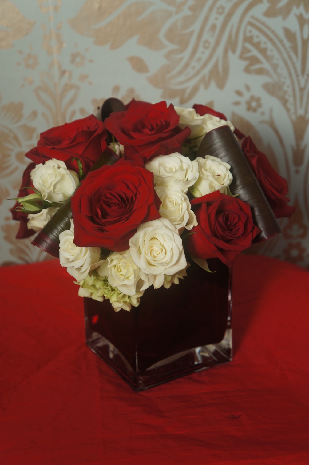 A red square vase filled with green hydrangea and topped off with