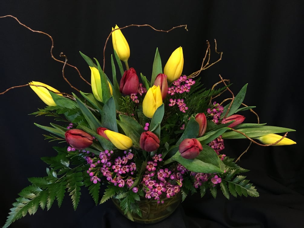 Bowl full of tulips and filler flower plus whimsical willow branches. Colors