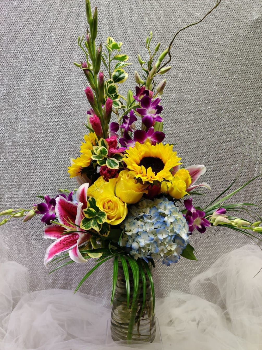 Gladiolus, Orchids, Sunflowers, Hydrangeas, Stargazer Lily, Roses, Willow, and Variegated greenery