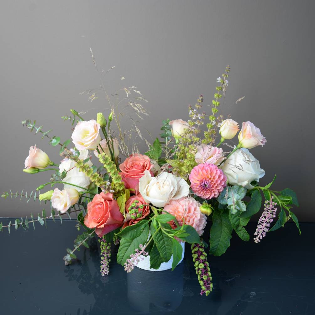 Delightful arrangement of white, blush and salmon colored blooms in a white
