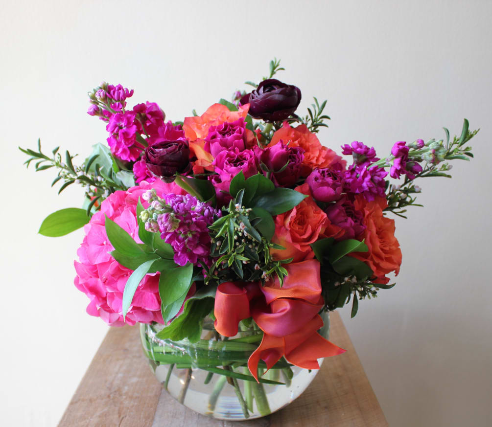 Hot pink and oranges. A mix of roses, stock and hydrangea arranged