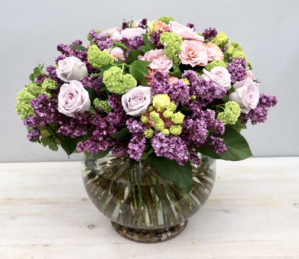 Standard size of this arrangement has roses lilacs and viburnum. Premium will