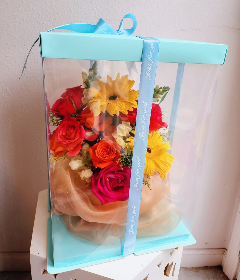 Beautiful robin&#039;s egg colored box with bright blooms in display. Arrangement comes
