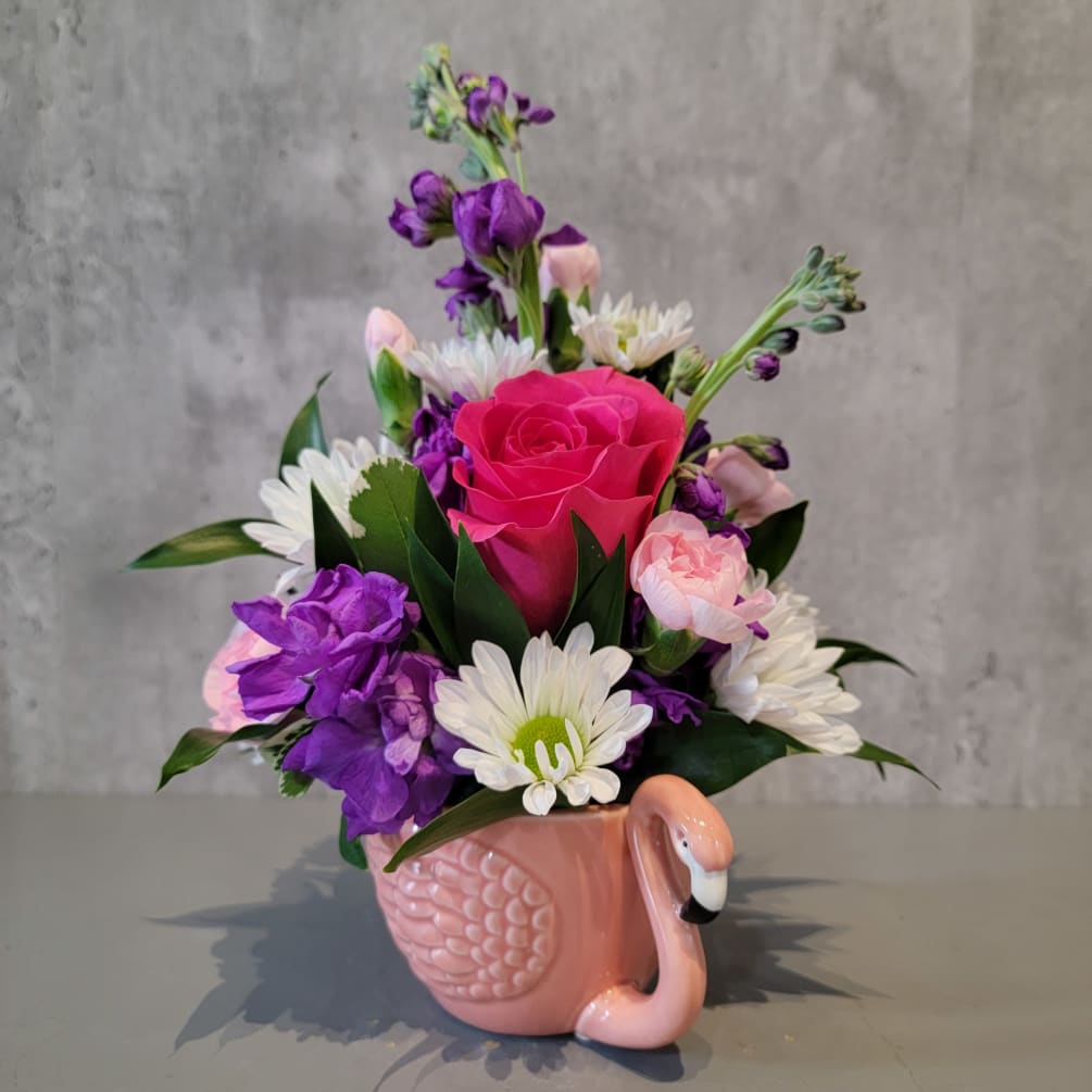 Cute flamingo mug with pink, purple and white flowers. The arrangement is