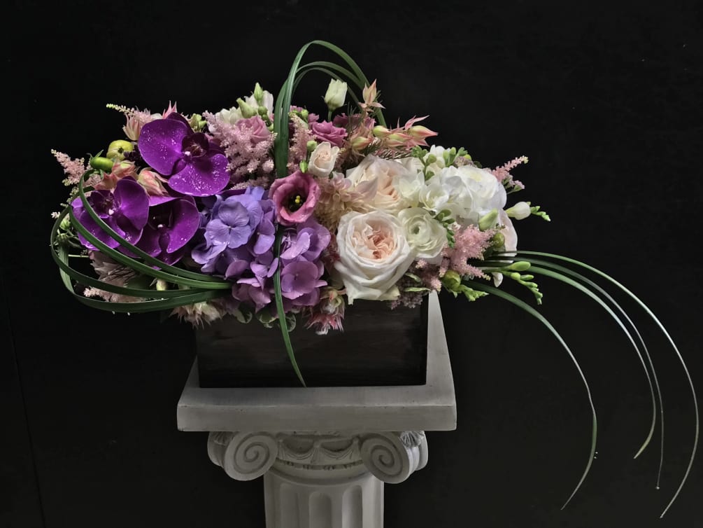 Asymmetrically designed table piece featuring phalaenopsis orchids, lavender hydrangea.