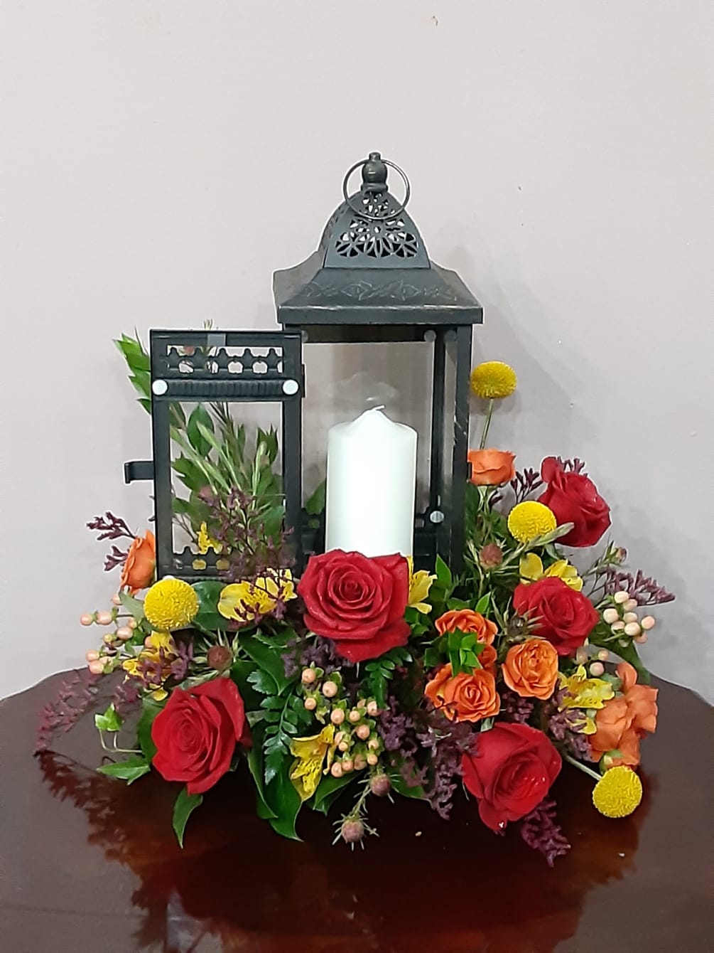 A rustic wooden lantern with fresh flowers spilling out and a pillar
