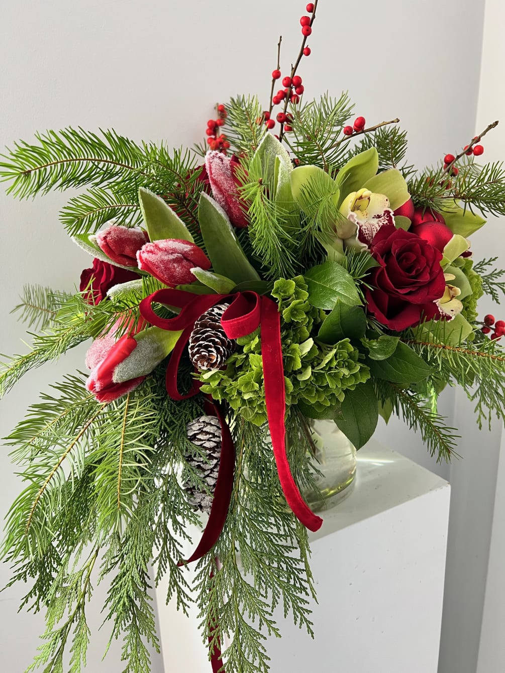 Beautiful arrangement filled with roses, orchids tulips, ilex berries Christmas greens