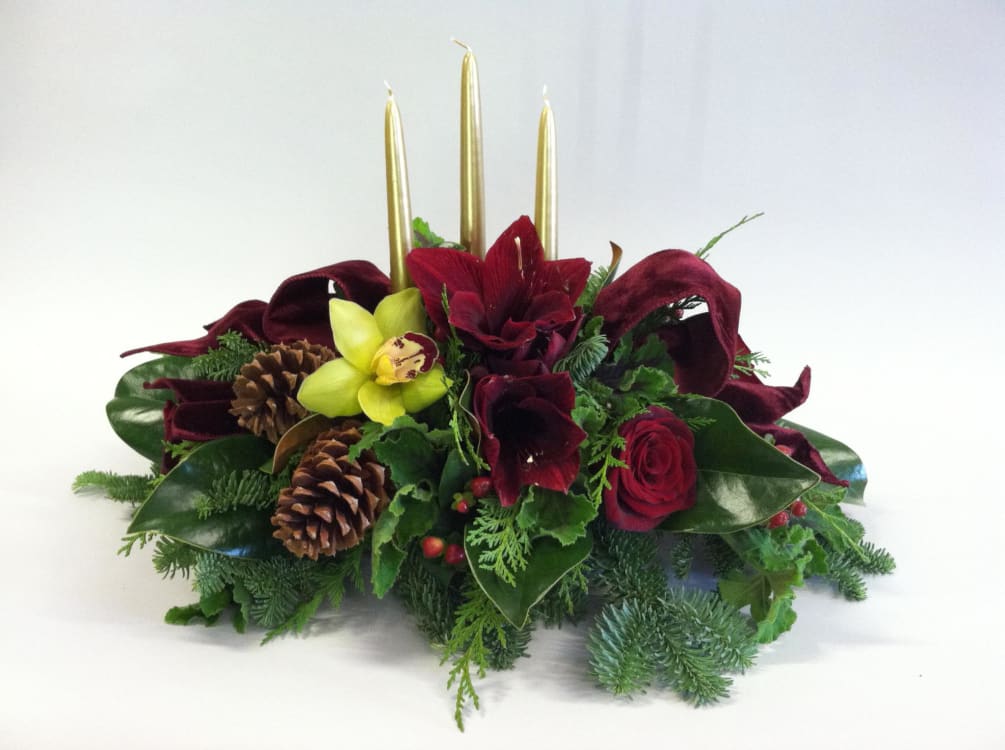 Christmas centerpiece with evergreens, candles, pinecones, amaryllis and orchids