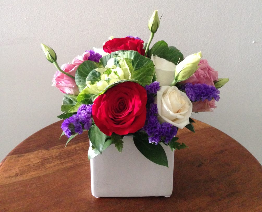 Multicolored surprise with purple statice, white kale and a variety of roses.