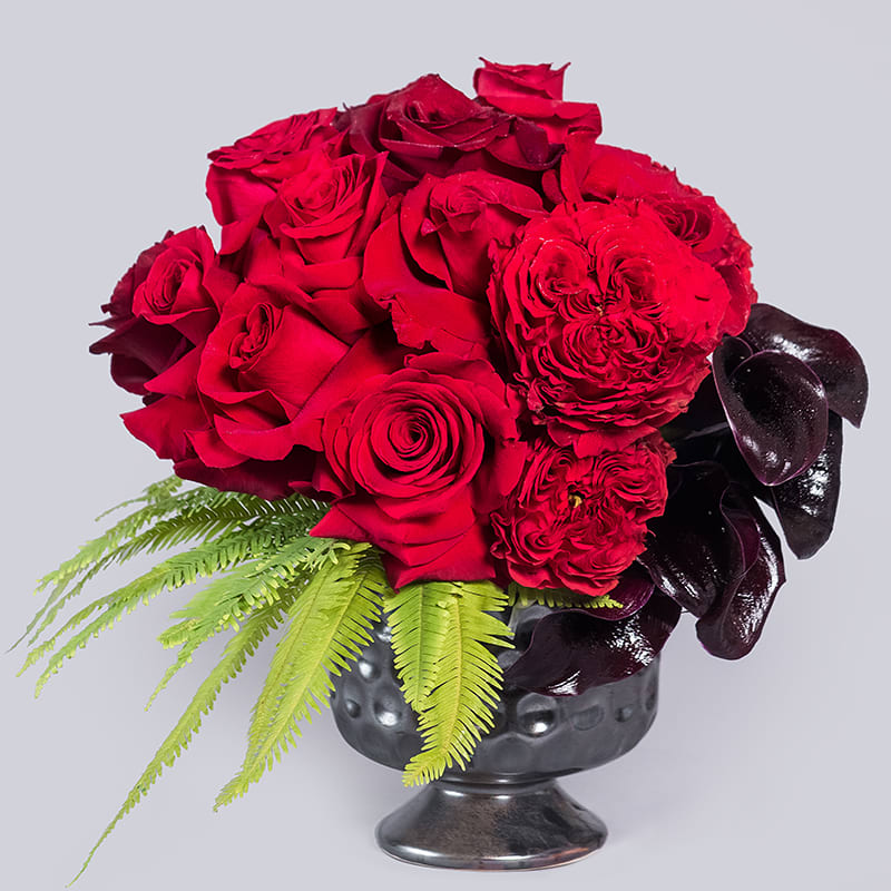 A modern red and black arrangement full of bright red roses, with