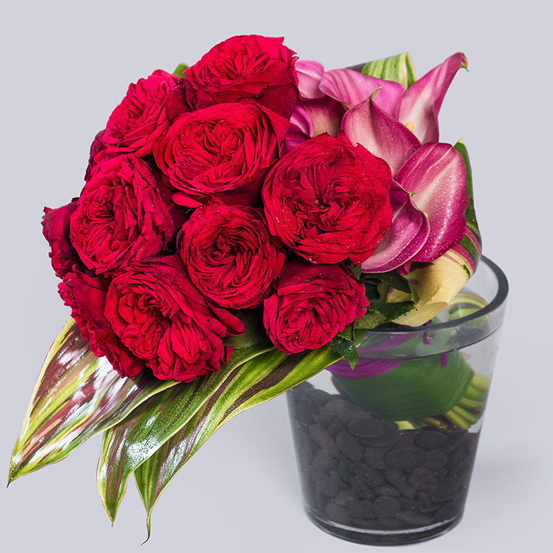 A short and sweet arrangement of deep red roses and pink mini