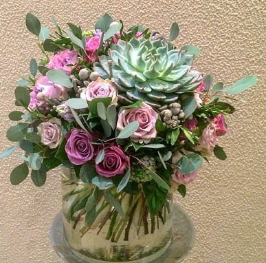 Designed in a cylinder vase, purple roses, hyacinths, fillers and a variety