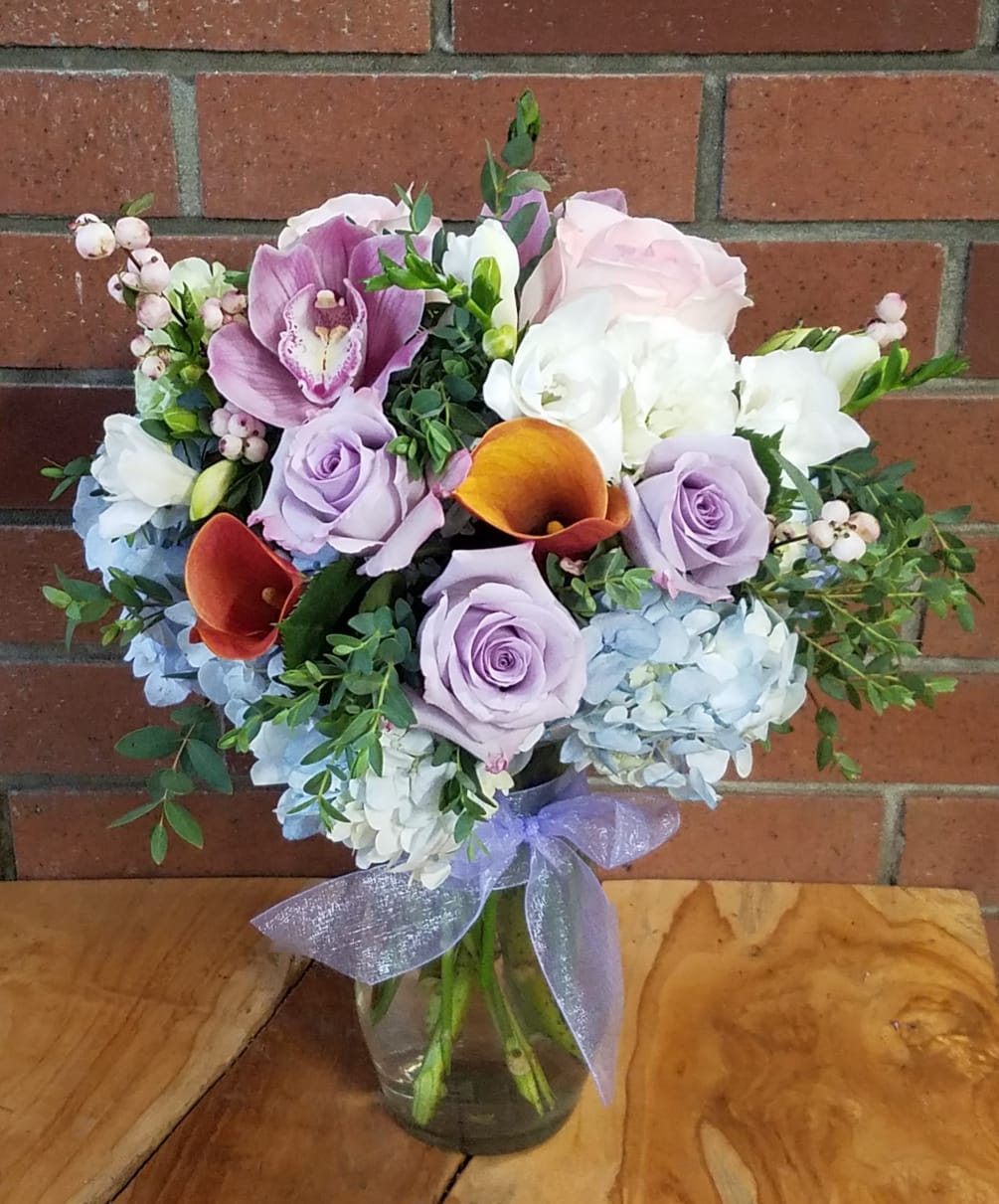 Sweet lavender roses, blue hydrangeas, touches of white freesia, a cymbidium orchid