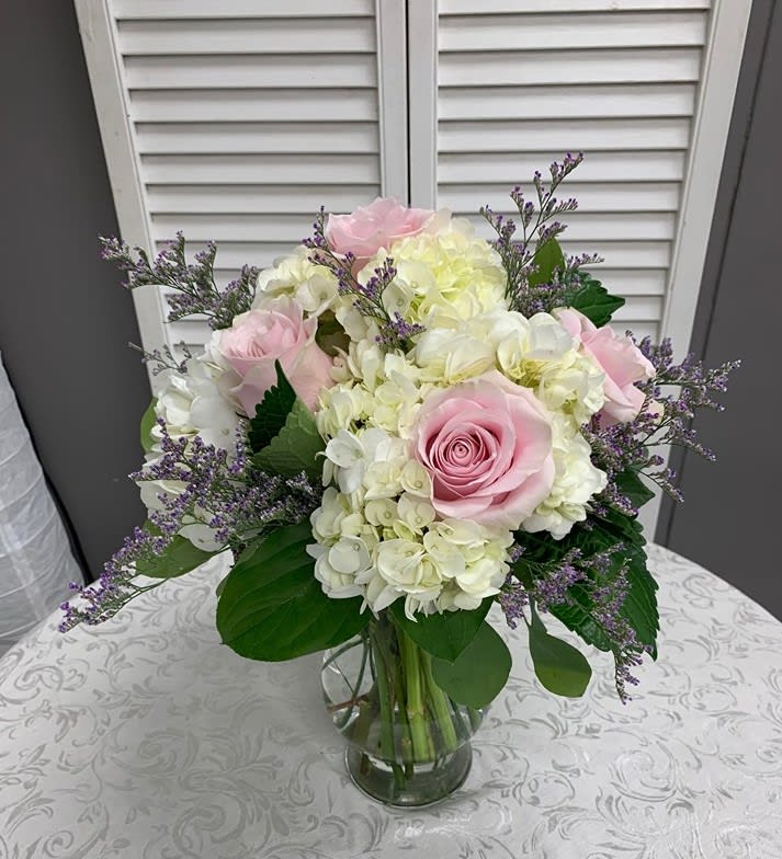 Hydrangeas, pink roses and purple accent in a decorative vase