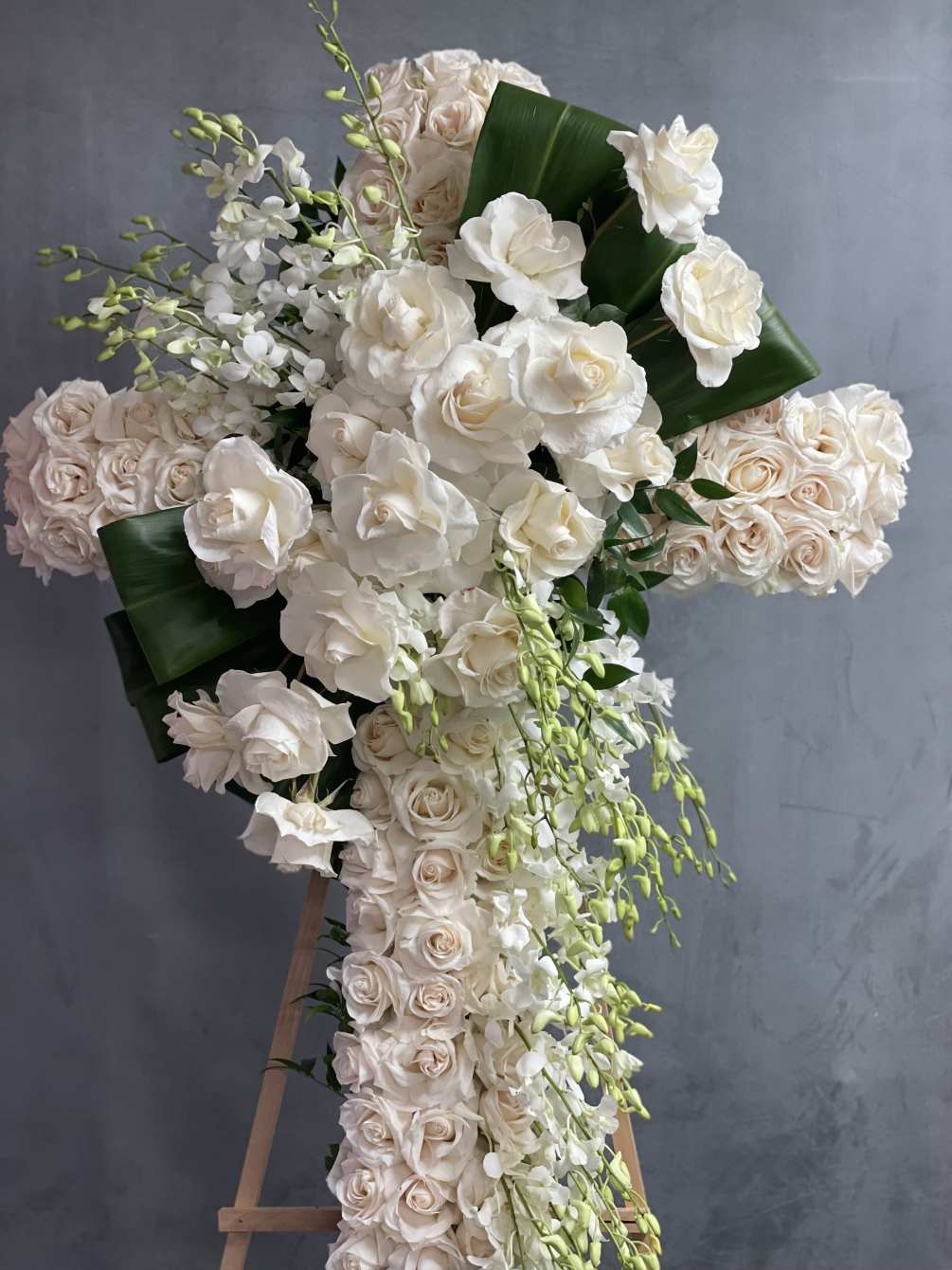 Cross filled with orchids and roses .
Each arrangement recreated this item description