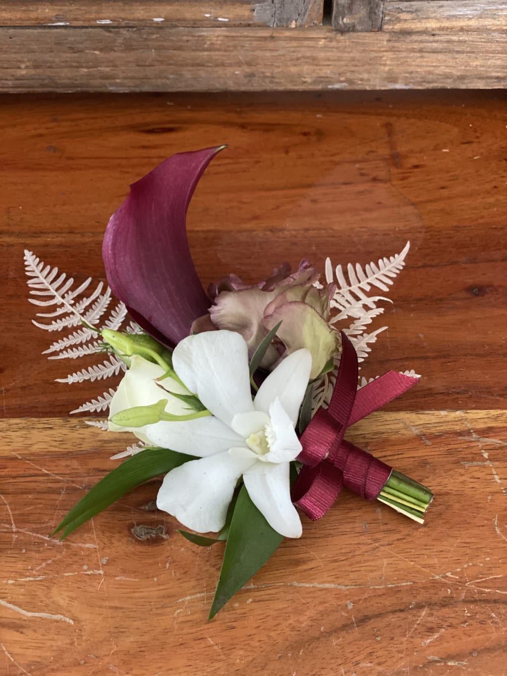A boutonniere for many different occasions featuring an orchid and mini calla