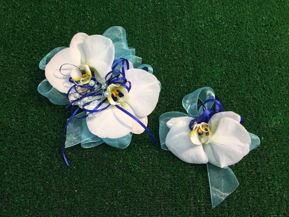 A set of corsage and boutonniere with orchids and accents in white