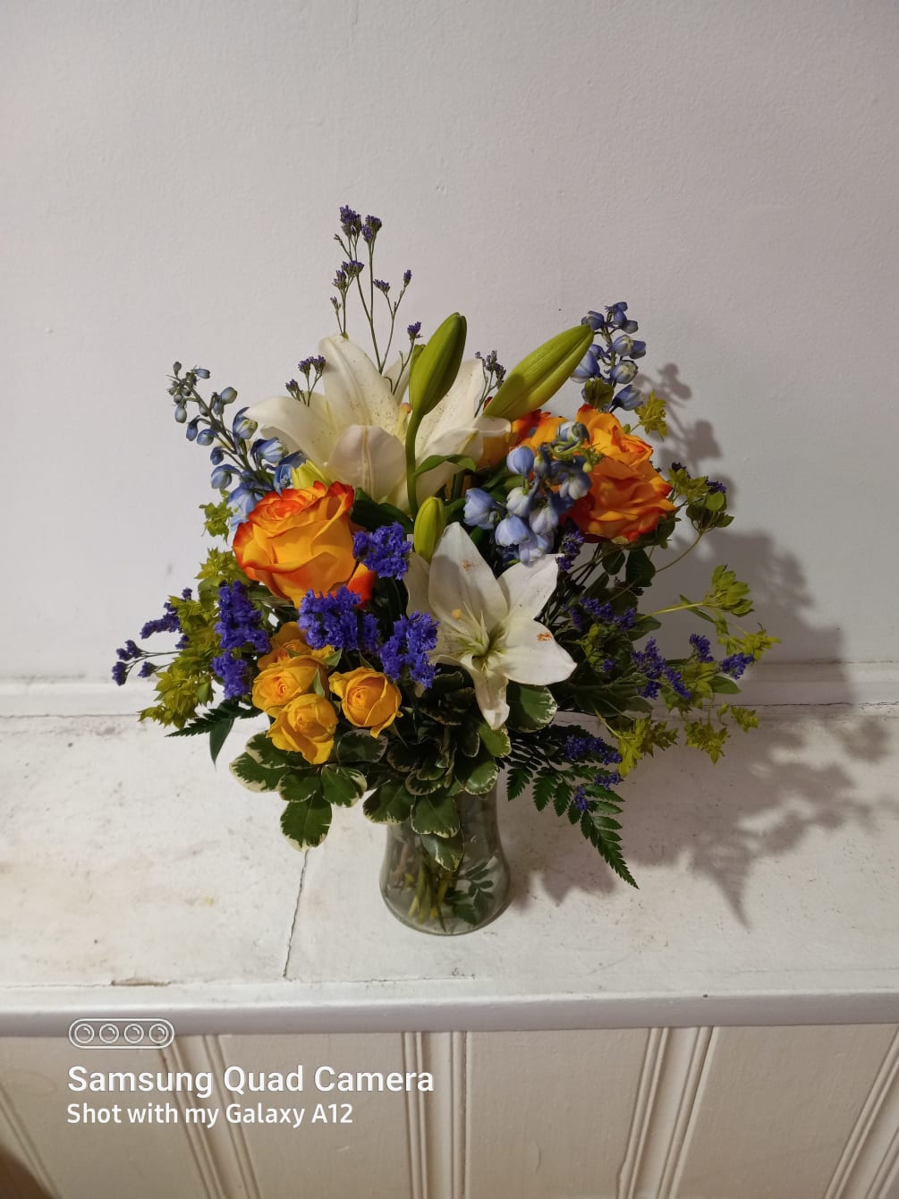 Beautiful white oriental lilies, yellow roses and blue delphinium with greenery and