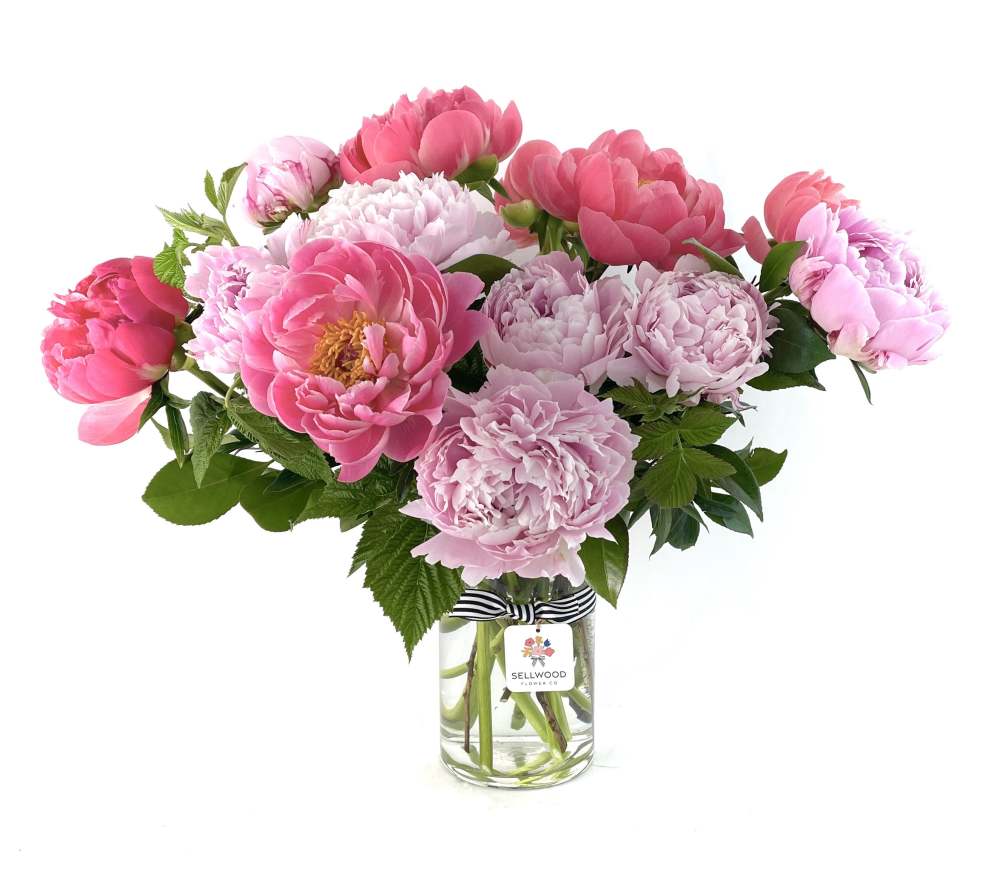 One dozen Oregon grown peonies artfully arranged in a clear cylinder adorned