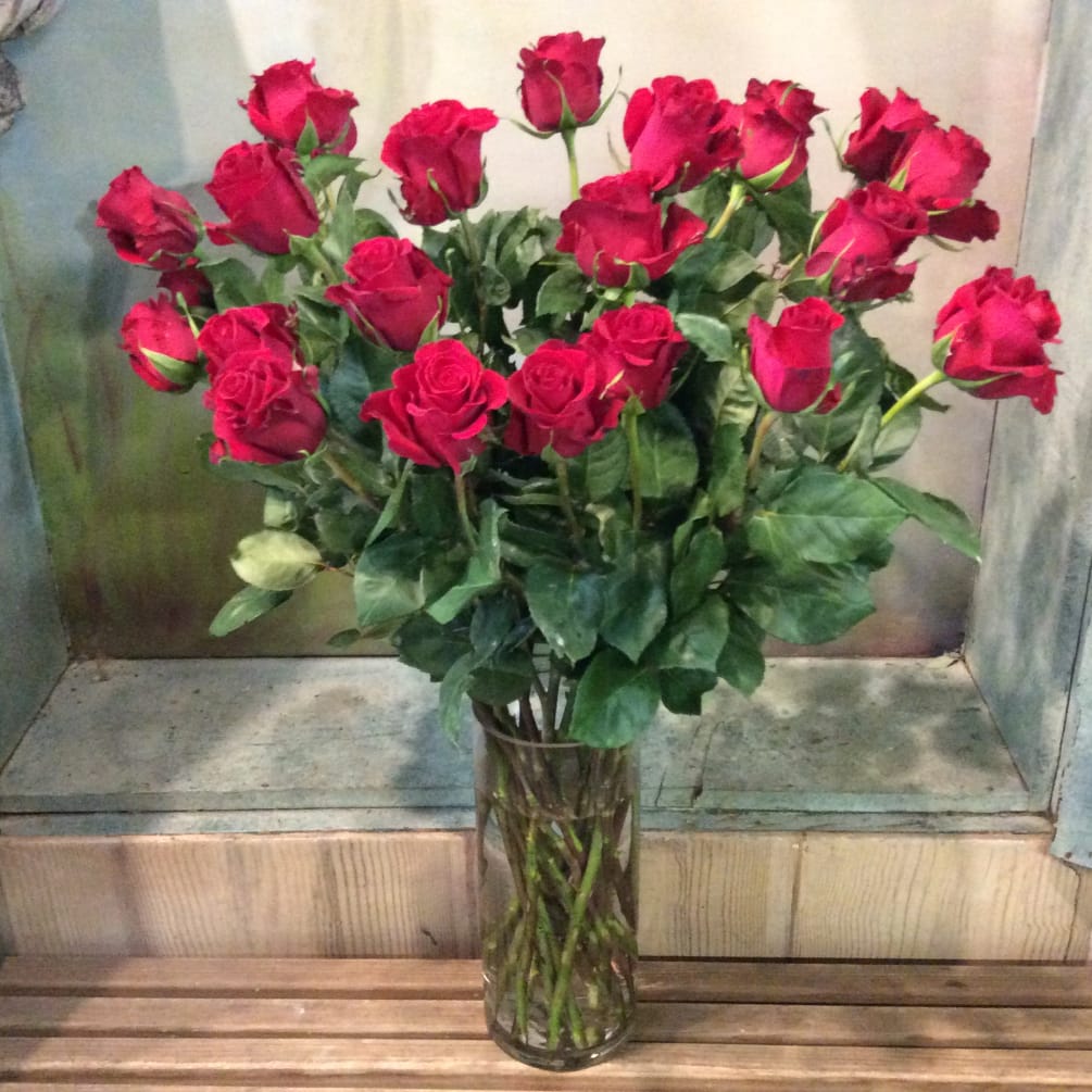 Two dozen red roses in clear glass.