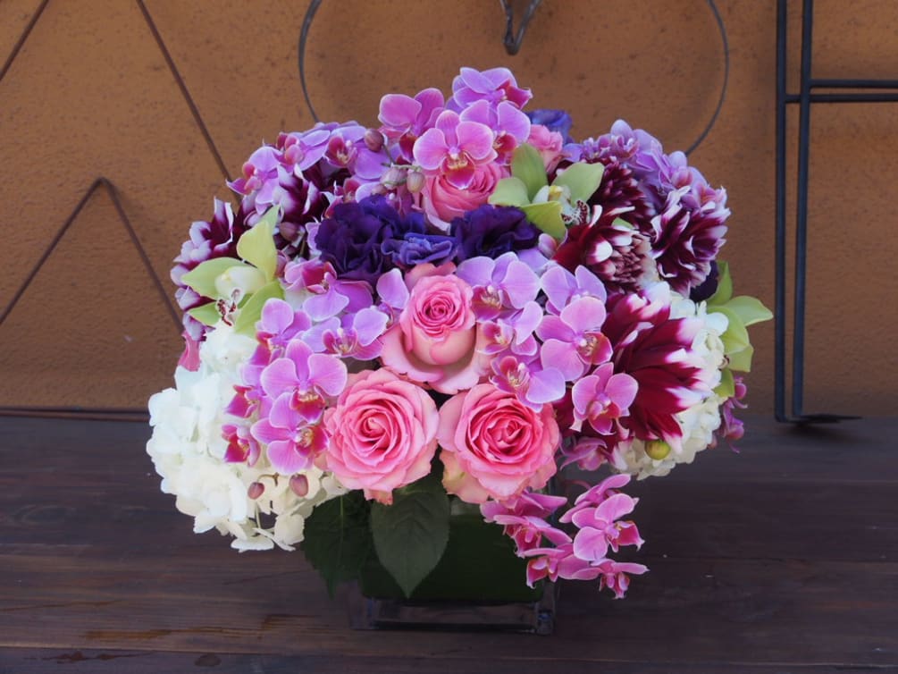 6&quot; sqare vase with lush arrangement in the pink/purple colors. Arrangement 
to