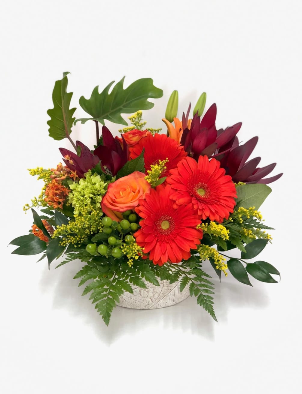 Blazing tropical colors arranged together in a nice ceramic container. Gerbers, roses