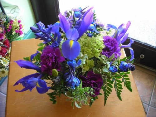 Square vase, contemporary look. Flowers included: Blue iris, green hydrangea,Purple carnations,Blue delphiniumAssorted